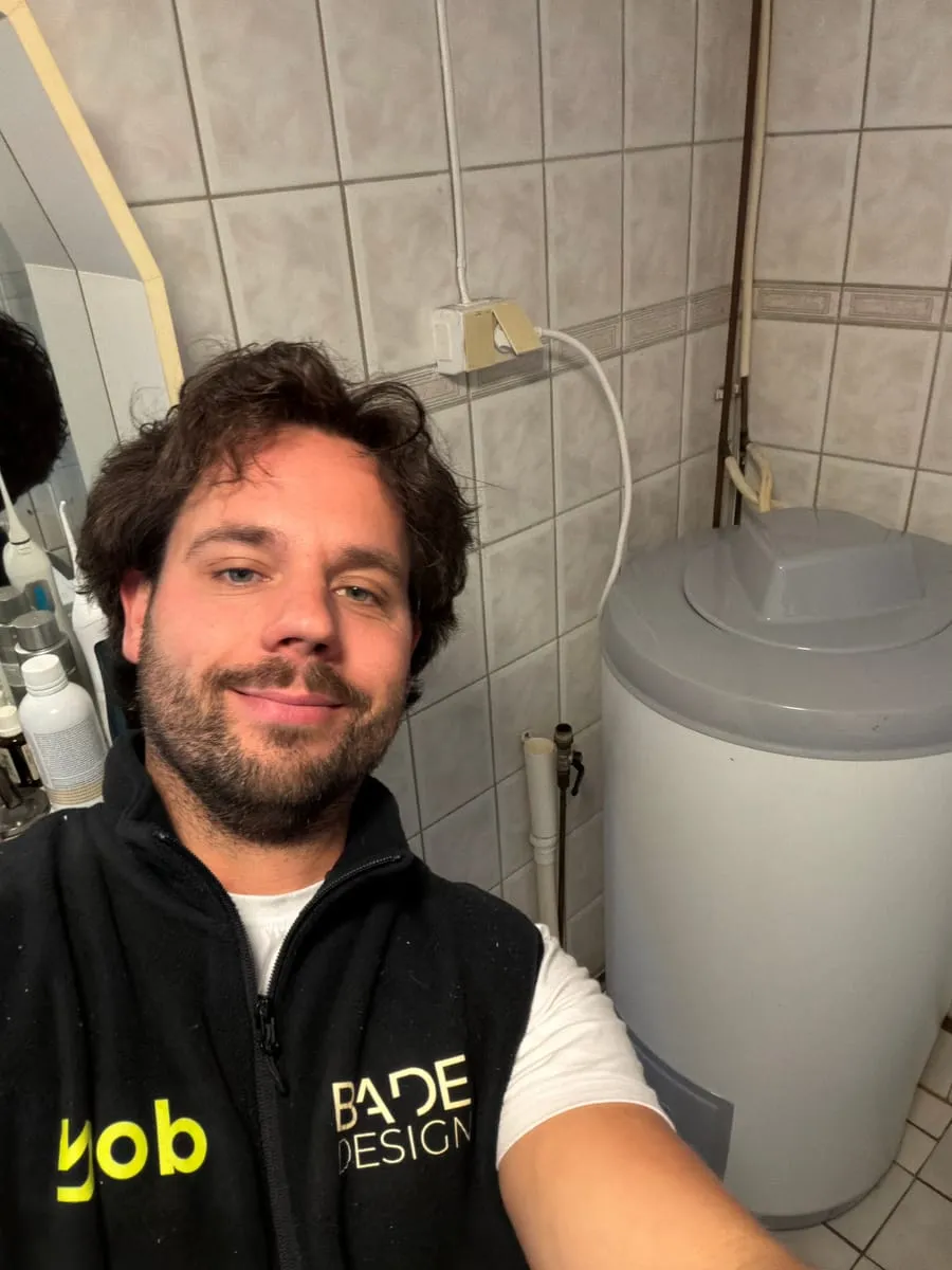 Rørlegger fra YOB foran den nye varmtvannsberederen han nettopp har montert på badet